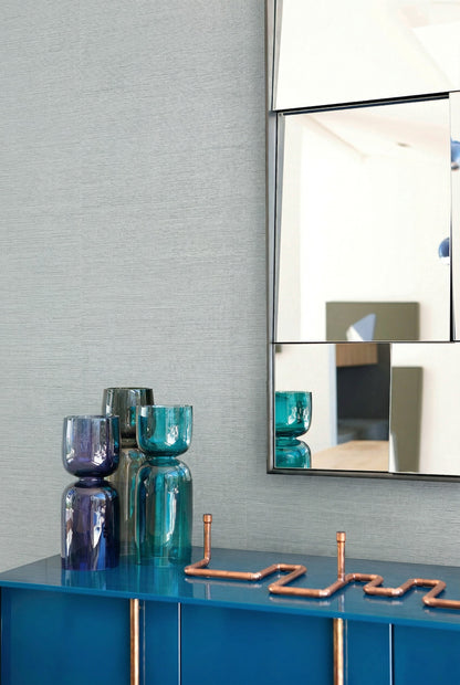Modern decor with blue glass vases, a geometric mirror, and Sisal Texture Grasscloth Naturals wallpaper.