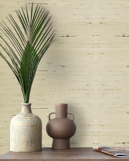 A vase with a palm leaf and another vase sit by a magazine against Straw Texture Grasscloth Naturals wallpaper.