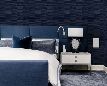 Modern bedroom with a navy bed, white bedding, and an accent wall in Industrial Grasscloth Stripe Vinyl wallpaper.