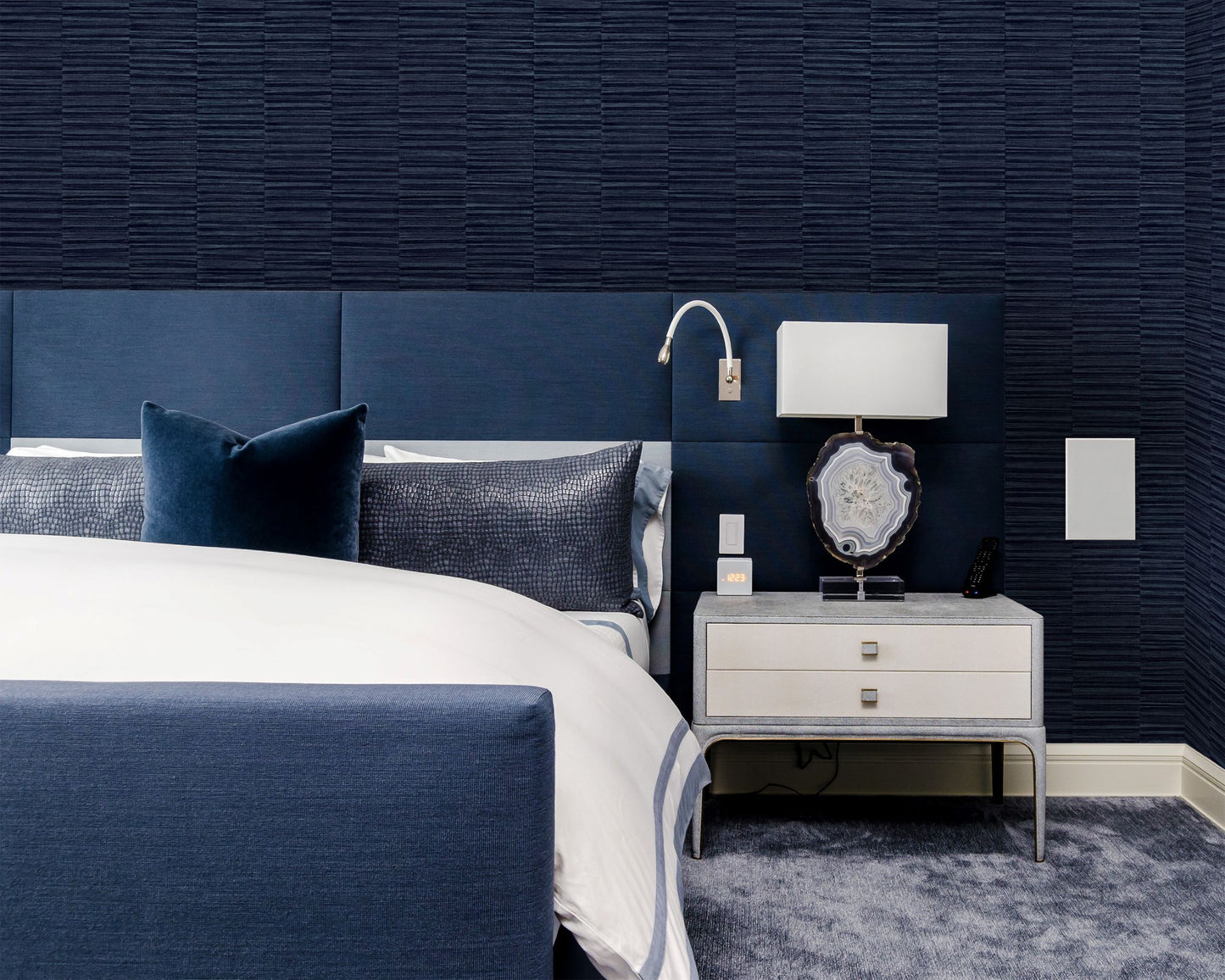 Modern bedroom with blue upholstered headboard and wall decorated with Blue Industrial Grasscloth Stripe Commercial & Vinyl.
  