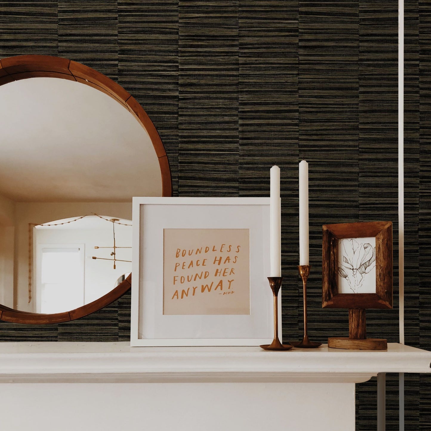 Decorative items on a shelf including a mirror, framed text, and candles against a wall decorated with Brown Industrial Grasscloth Stripe Commercial & Vinyl.
