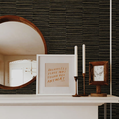 Decorative items on a shelf including a mirror, framed text, and candles against a wall decorated with Brown Industrial Grasscloth Stripe Commercial & Vinyl.
