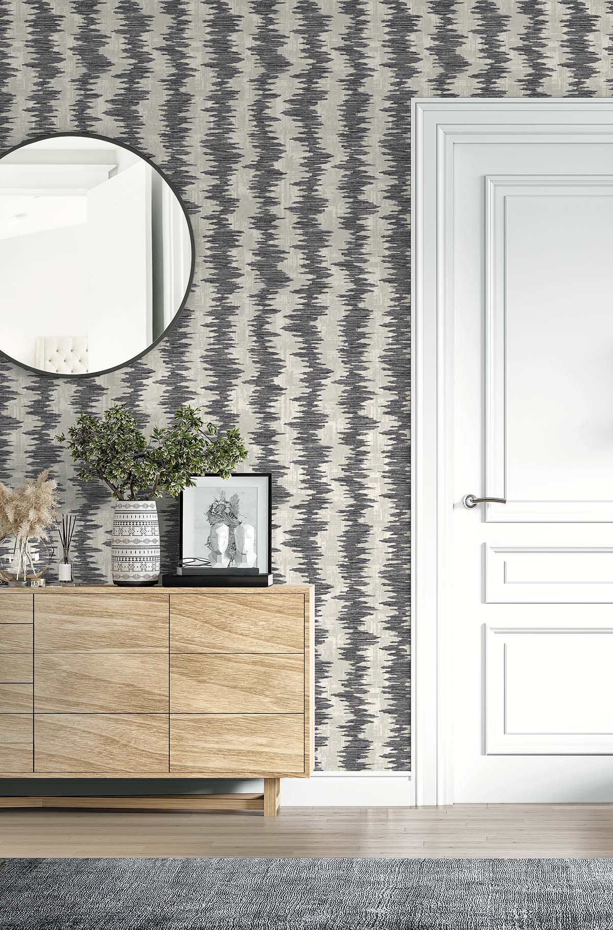 Modern interior with a round mirror, Ikat Stripe Wallpaper, wooden sideboard, and a sleek white door.