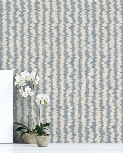 Two potted orchids on a white floor in front of beige and blue Ikat Stripe Wallpaper.