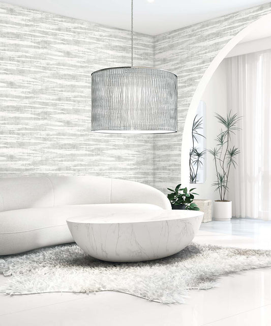 Modern living room with a curved white sofa, round coffee table, gray rug, plants, and Stone Nebulite Wallpaper accents.