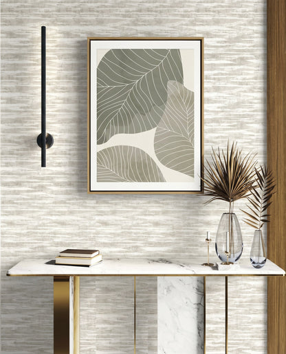 Modern console table with books, vases, and abstract leaf art on Stone Nebulite Wallpaper with a black wall sconce.