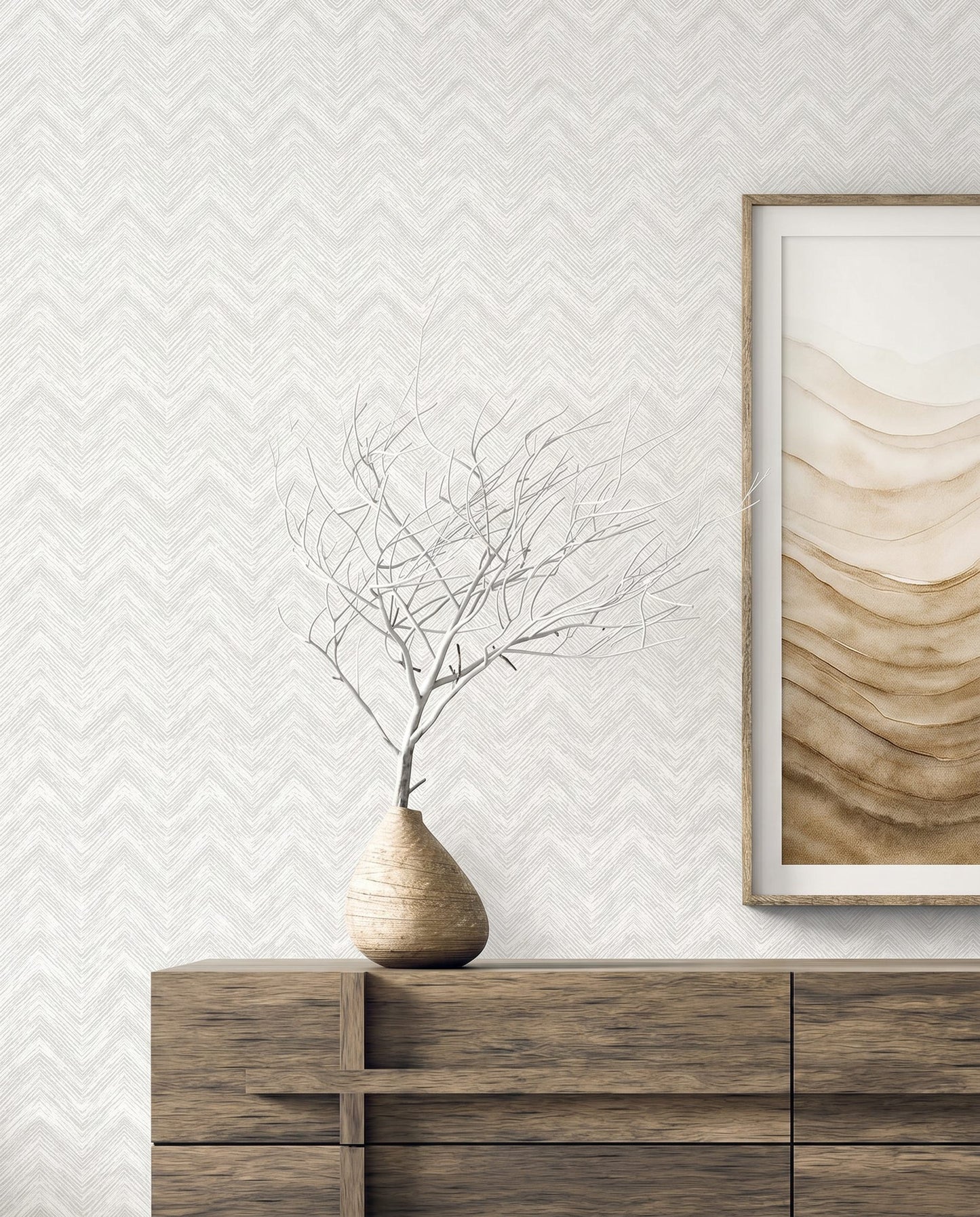 A minimalist wooden sideboard with a bare branch and abstract art on cream Chevron Wallpaper.
