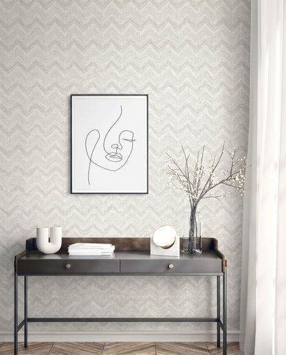 Minimalist console table with decor and vase, featuring face line art on a wall with Chevron Wallpaper.