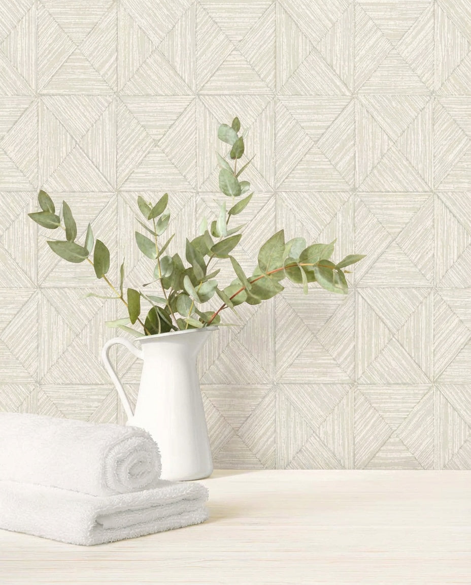 White pitcher with eucalyptus and towels sits by a wall with Inlay Tile Wallpaper in a geometric pattern.