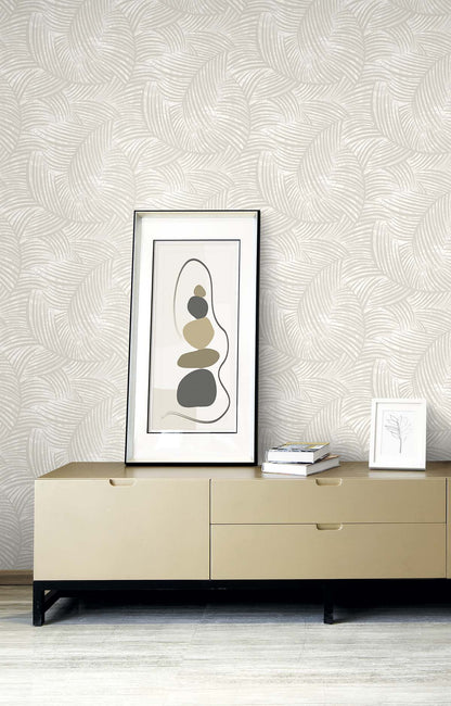 Beige sideboard with abstract art, books, and framed print against Palm Fronds Wallpaper in cream.