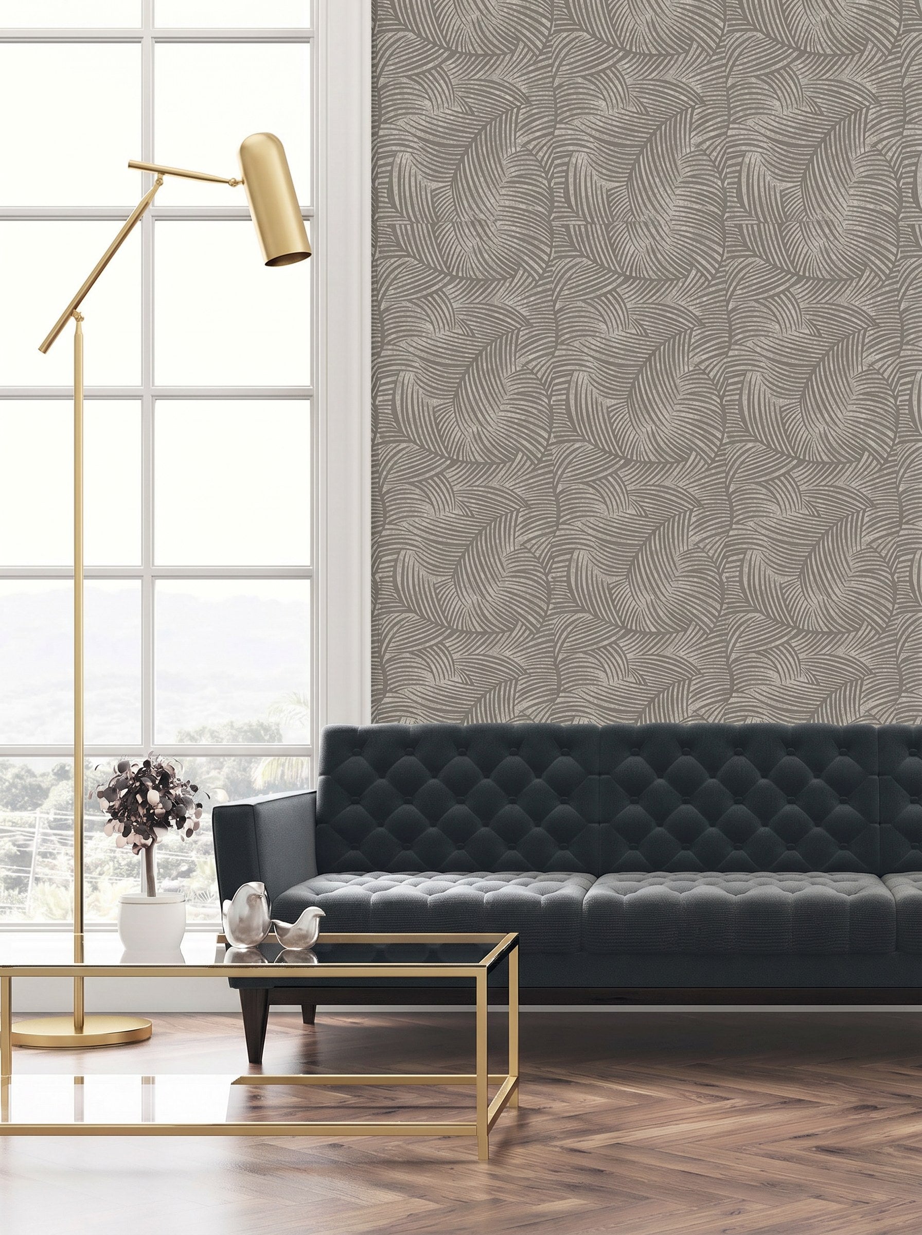 Modern living room with a dark blue tufted sofa, gold lamp, glass table, and Palm Fronds Wallpaper.