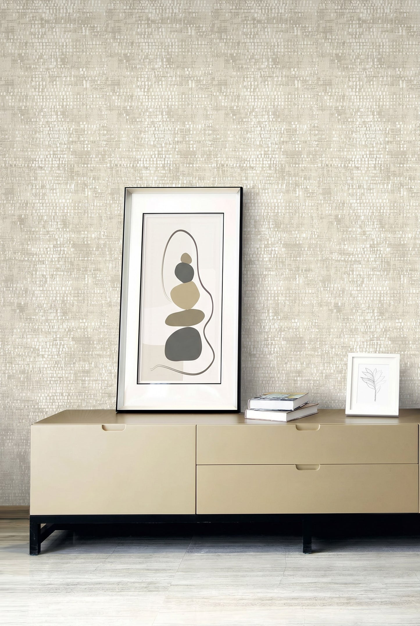 Minimalist sideboard displaying art, books, and a sketch set against washable, textured Dotted Wallpaper in beige.