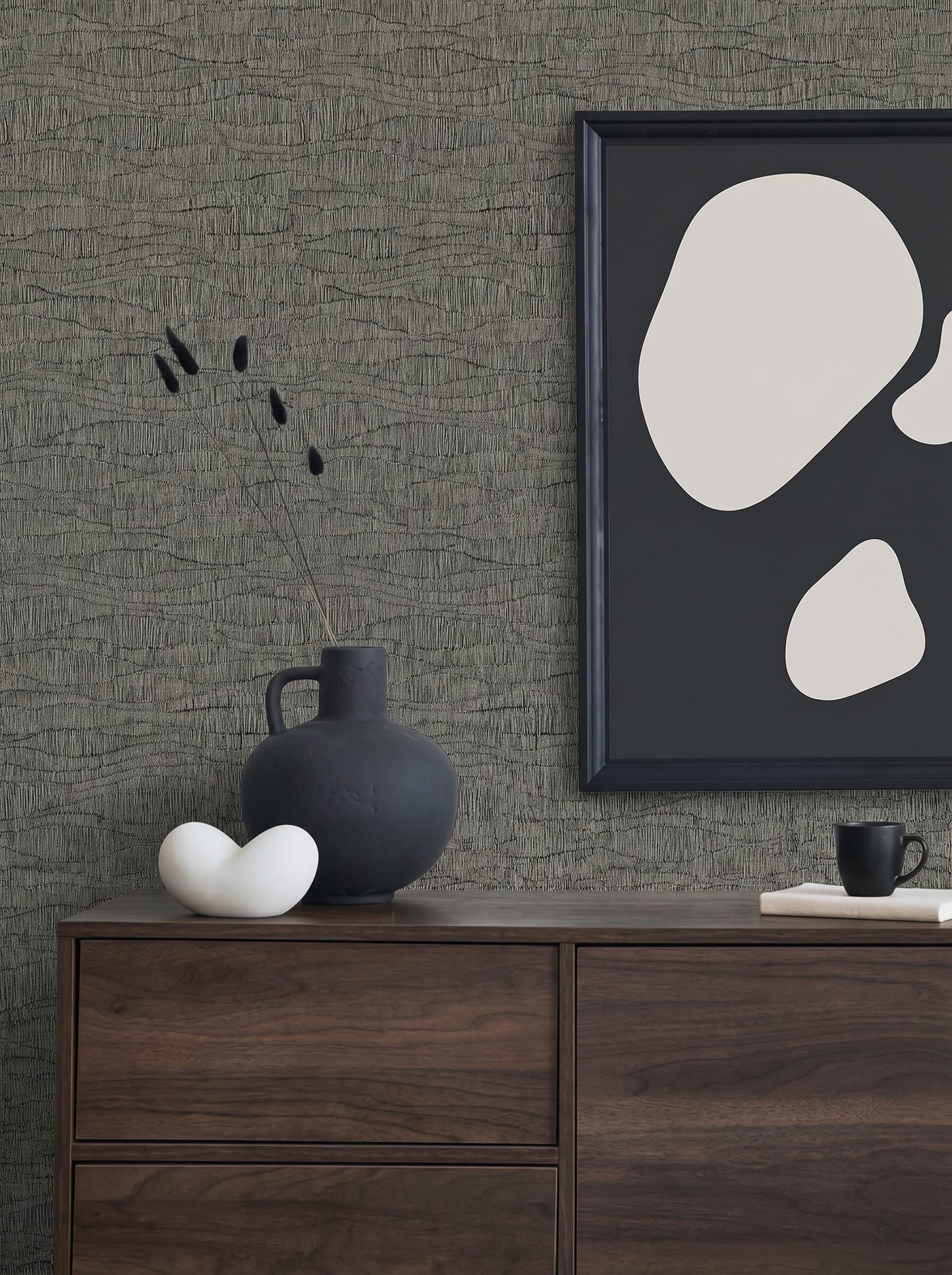 Minimalist decor with a dark vase, abstract art, ceramics on a dresser against Wavy Wallpaper.
