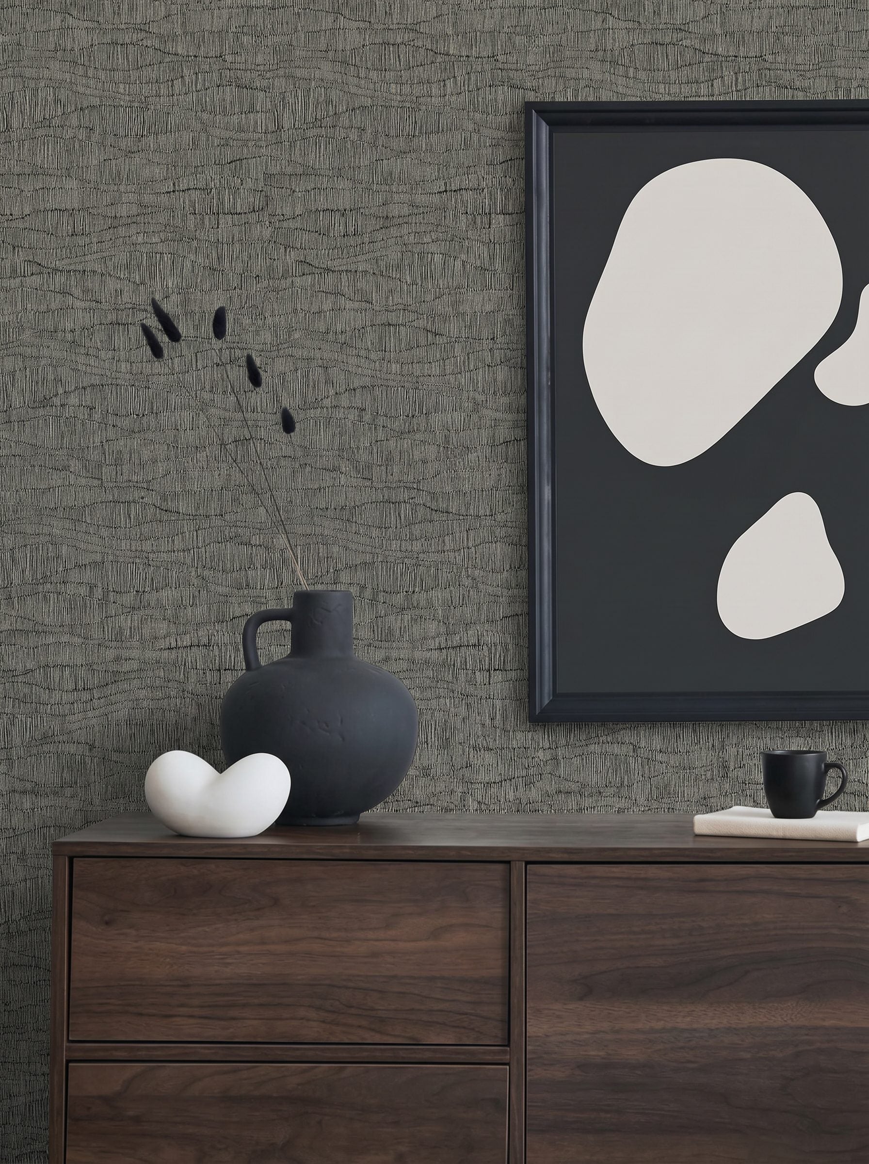 Minimalist decor with a dark vase, abstract art, ceramics on a dresser against Wavy Wallpaper.
