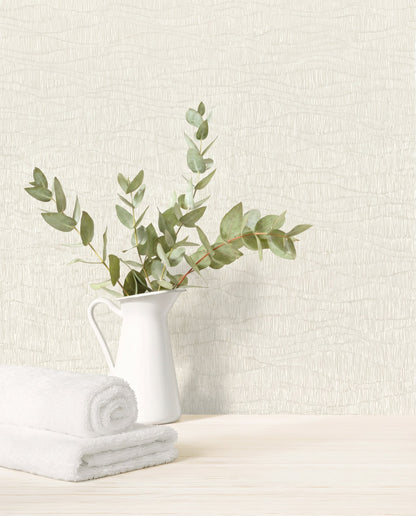 A white pitcher with green eucalyptus beside rolled towels on a light wood surface with Wavy Wallpaper.