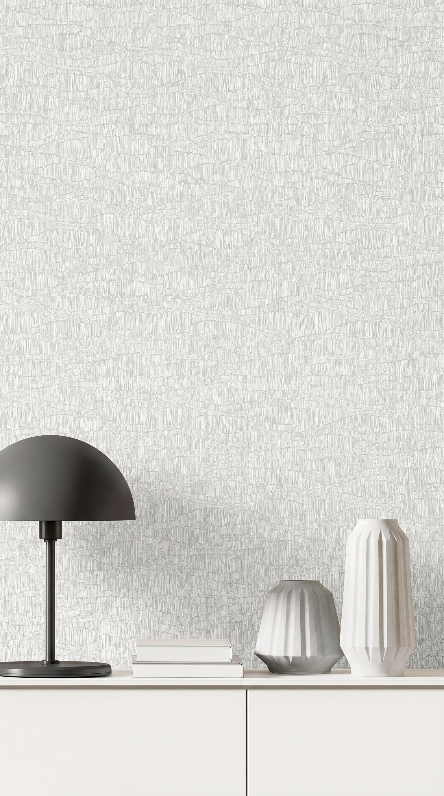 A minimalist white sideboard with vases, a black lamp, and books set against Wavy Wallpaper.