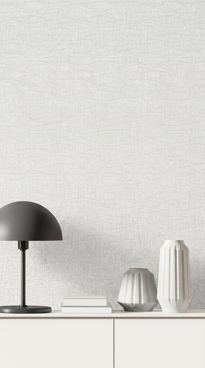 A minimalist white sideboard with vases, a black lamp, and books set against Wavy Wallpaper.