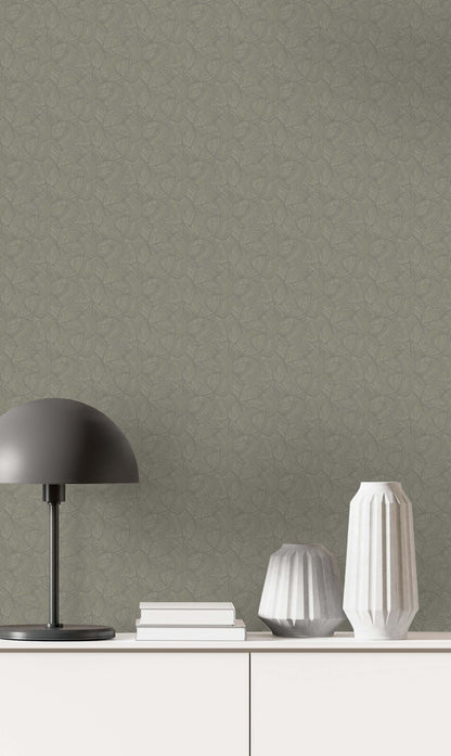 A black lamp, two white vases, and books rest on a white cabinet against Fan Wallpaper in textured green.