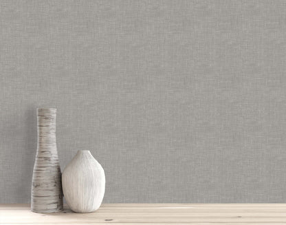 Two neutral-toned ceramic vases on light wood set against a gray Faux Linen Wallpaper wall.