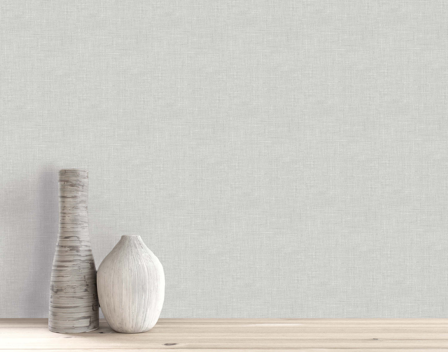 Two vases on a wooden surface with textured light gray Faux Linen Wallpaper as a washable backdrop.