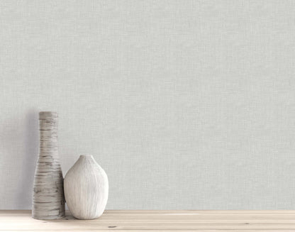 Two vases on a wooden surface with textured light gray Faux Linen Wallpaper as a washable backdrop.