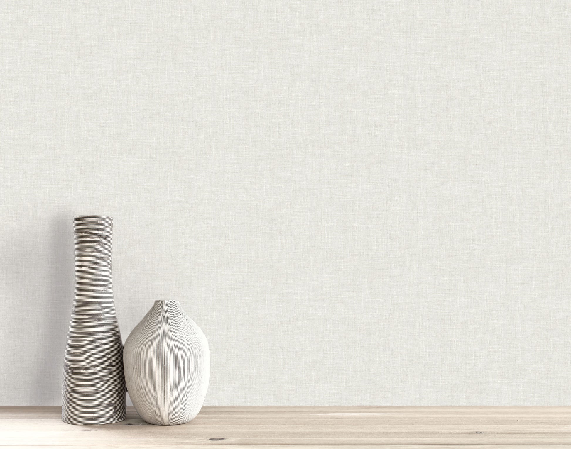 Two vases sit on a wooden surface against a light wall with subtle Faux Linen Wallpaper.
