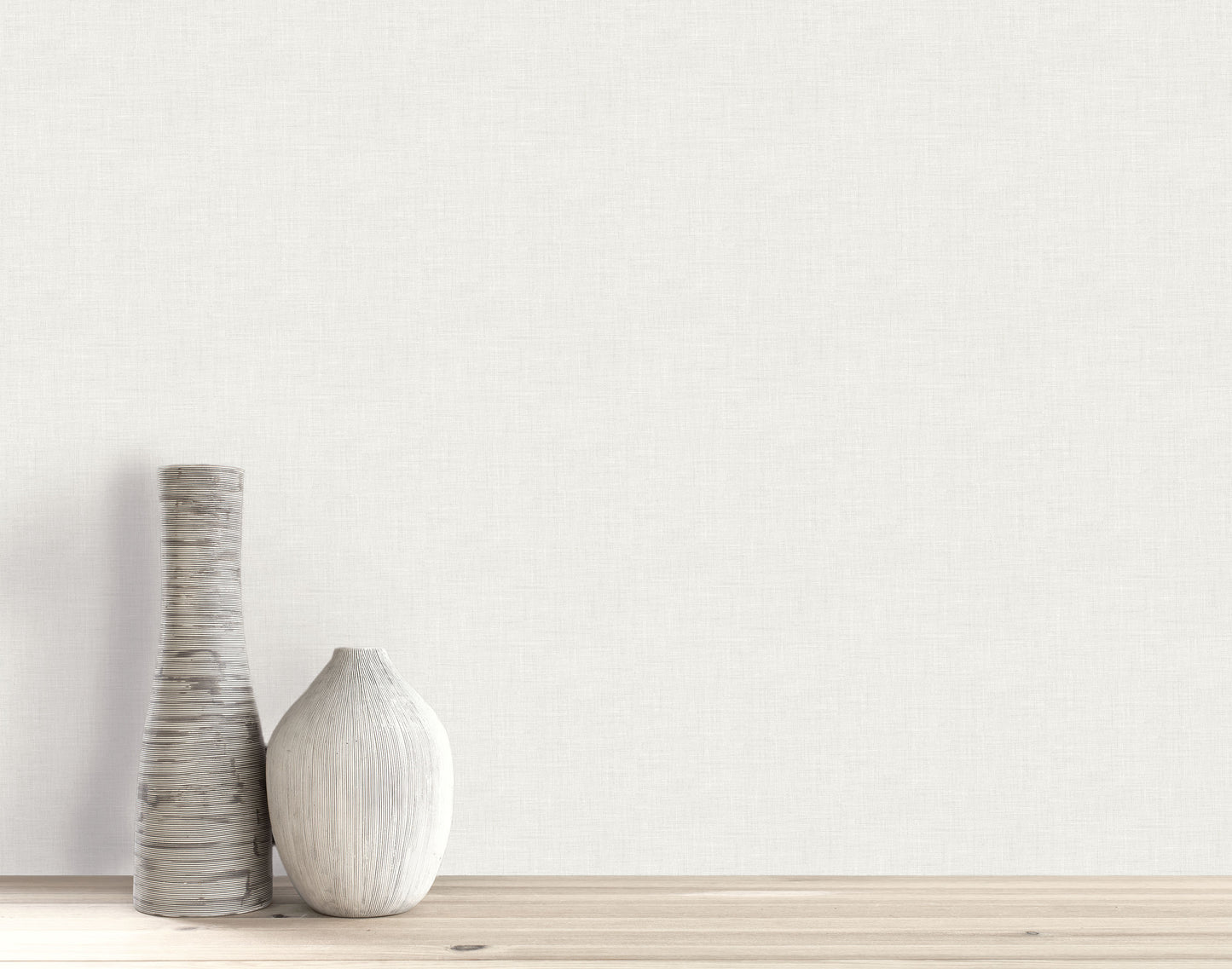 Two decorative ceramic vases on a wooden surface in front of a light Faux Linen Wallpapered wall.