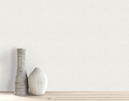 Two decorative ceramic vases on a wooden surface in front of a light Faux Linen Wallpapered wall.