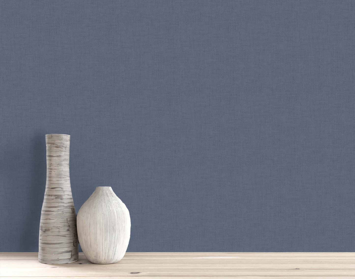 Two decorative vases on a light wooden surface against a plain blue Faux Linen Wallpaper background.