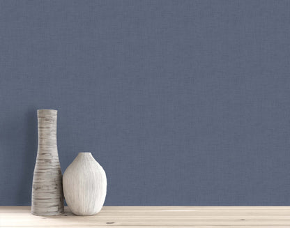 Two decorative vases on a light wooden surface against a plain blue Faux Linen Wallpaper background.
