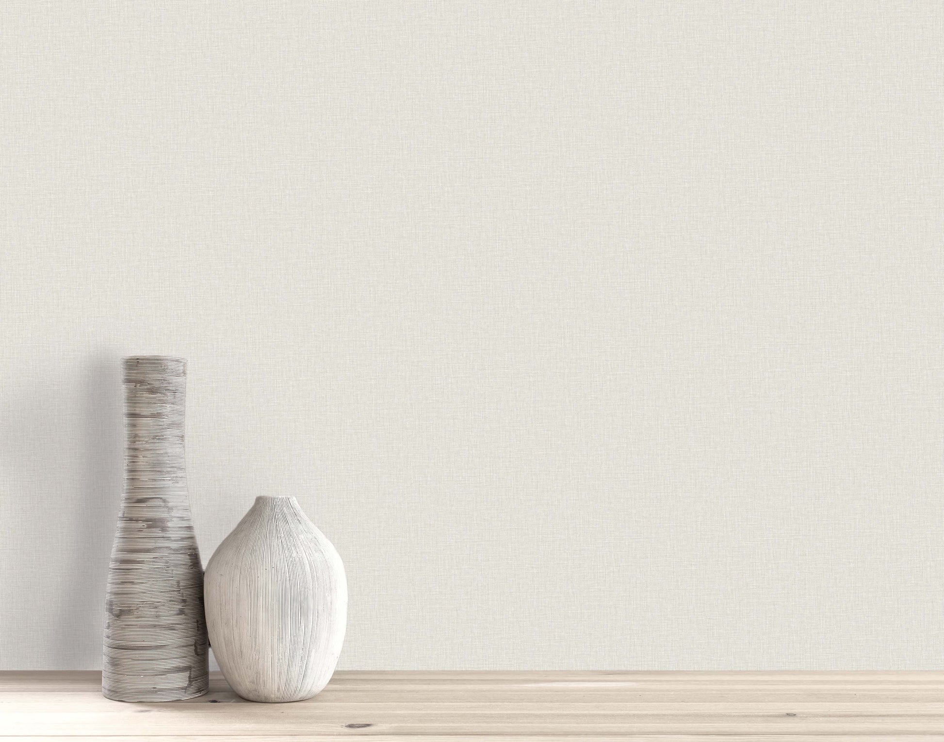 Two textured white vases on a light wooden surface against a Pearly Linen Wallpaper off-white wall.