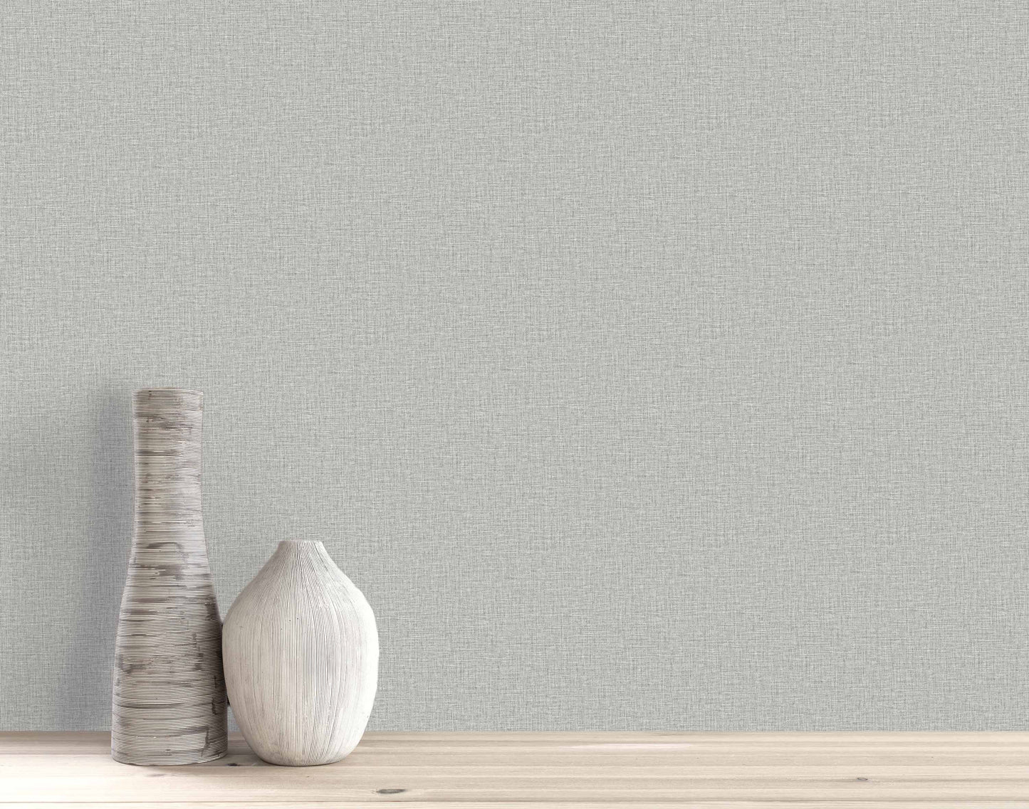 Two decorative vases sit on a wooden surface against a light gray Pearly Linen Wallpaper textured wall.