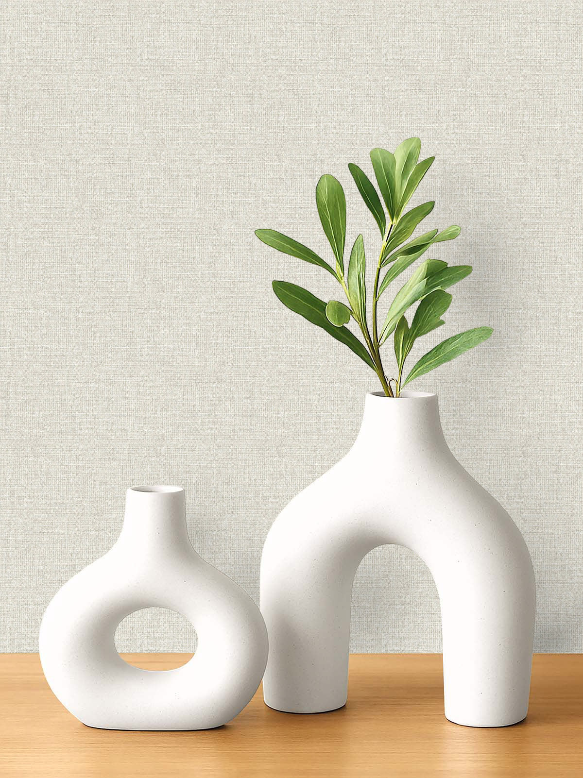 Two modern white ceramic vases on wood, set against light Woven Linen Effect Wallpaper.