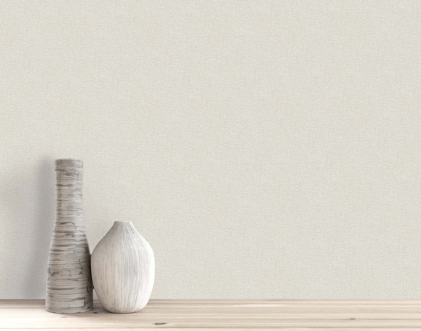 Two white, textured ceramic vases on light wood stand before Woven Linen Effect Wallpaper in light beige.