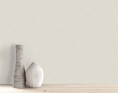 Two white, textured ceramic vases on light wood stand before Woven Linen Effect Wallpaper in light beige.