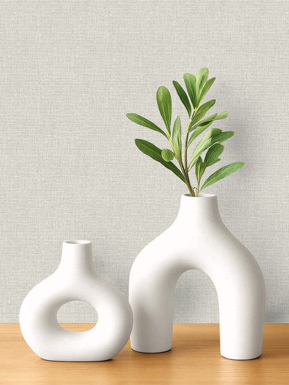 Two white ceramic vases on a wooden surface with Woven Linen Effect Wallpaper for a clean, fresh backdrop.