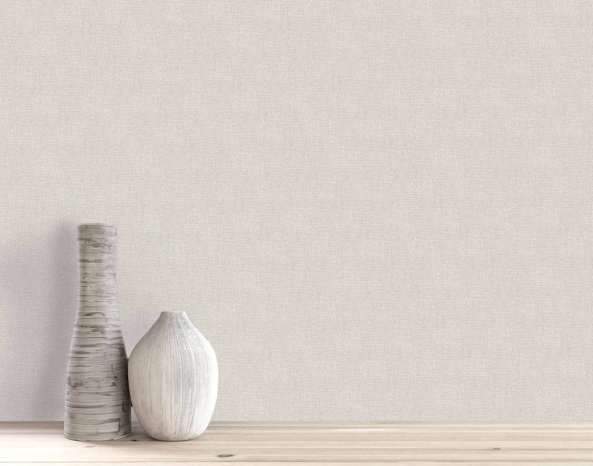 Two white ceramic vases on wood with a plain, light beige Woven Linen Effect Wallpaper background.