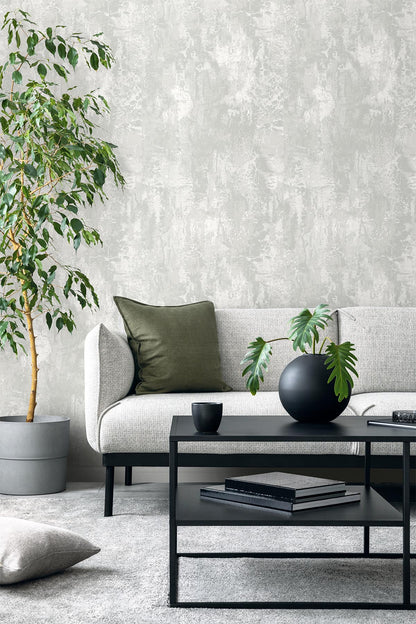 Modern living room with a gray sofa, green pillow, potted plant, and Faux Concrete Wallpaper.