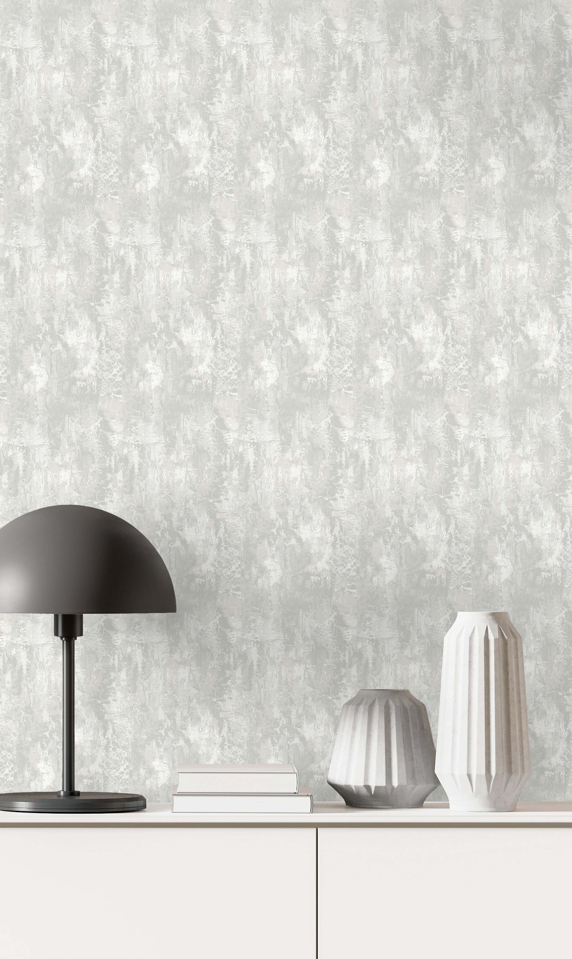 Minimalist scene with a black lamp, books, and vases on a white cabinet against Faux Concrete Wallpaper.