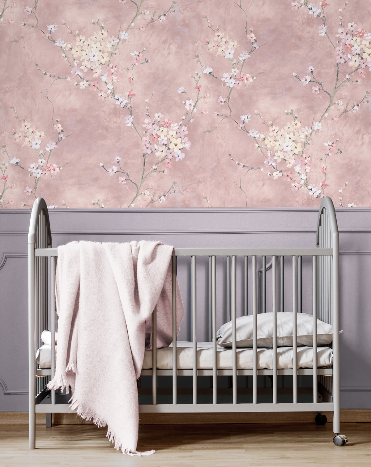 Baby crib with pink blanket against a wall decorated with Pink Blossom Branch Peel & Stick Casa Mia Wallcovering.
