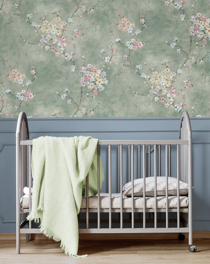 Crib with a green blanket against a wall decorated with Green Blossom Branch Peel & Stick Casa Mia Wallcovering.