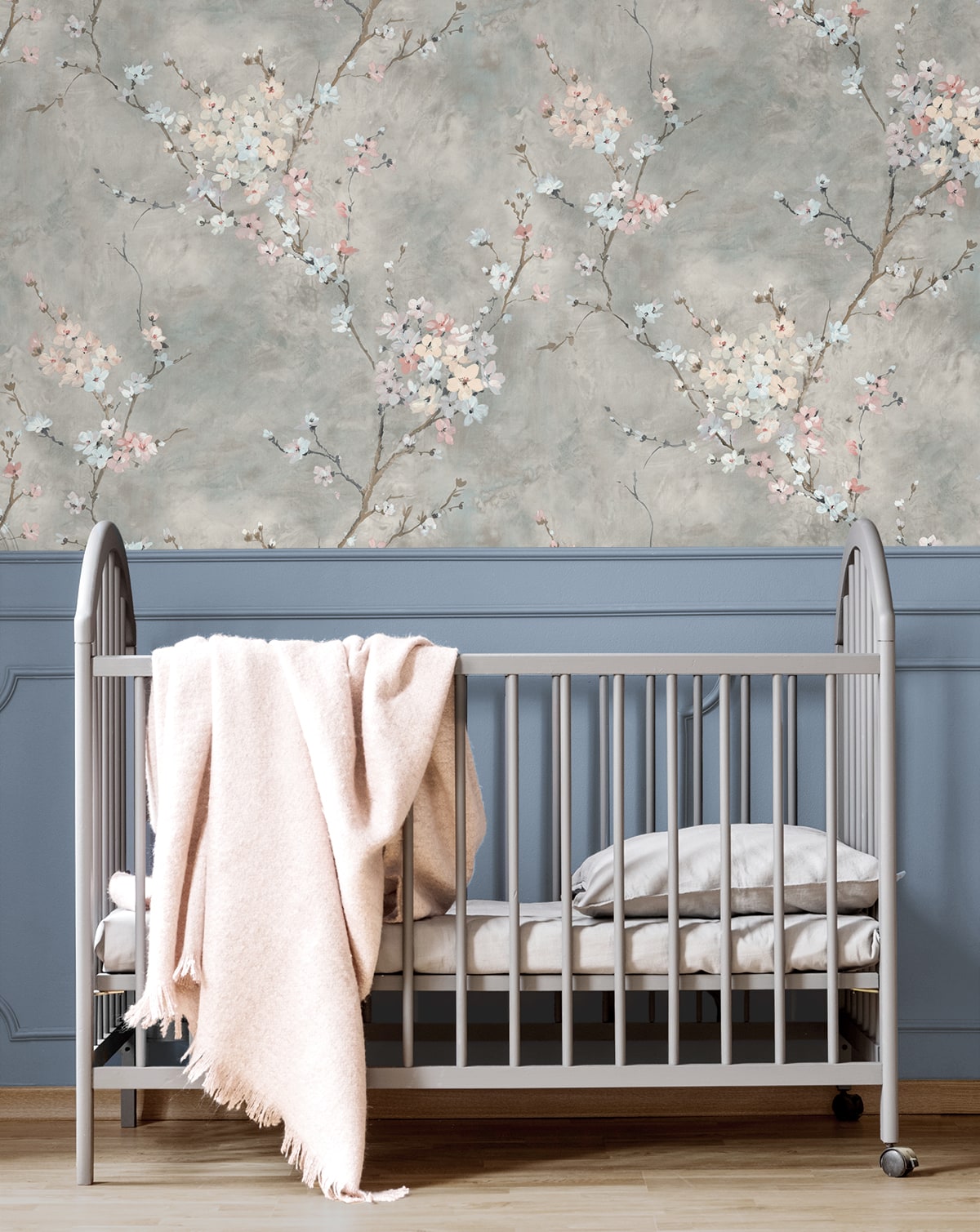 Silver crib with pink blanket against a wall decorated with Gray Blossom Branch Peel & Stick Casa Mia Wallcovering.