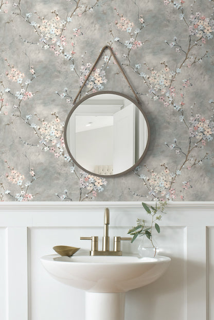 Round mirror hanging on wall decorated with Gray Blossom Branch Peel & Stick Casa Mia Wallcovering above a sink with a faucet.