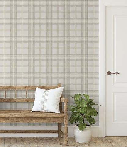 Wooden bench with a white pillow against a wall decorated with Gray Broken Twill Plaid Peel & Stick Casa Mia Wallcovering and a plant beside it.