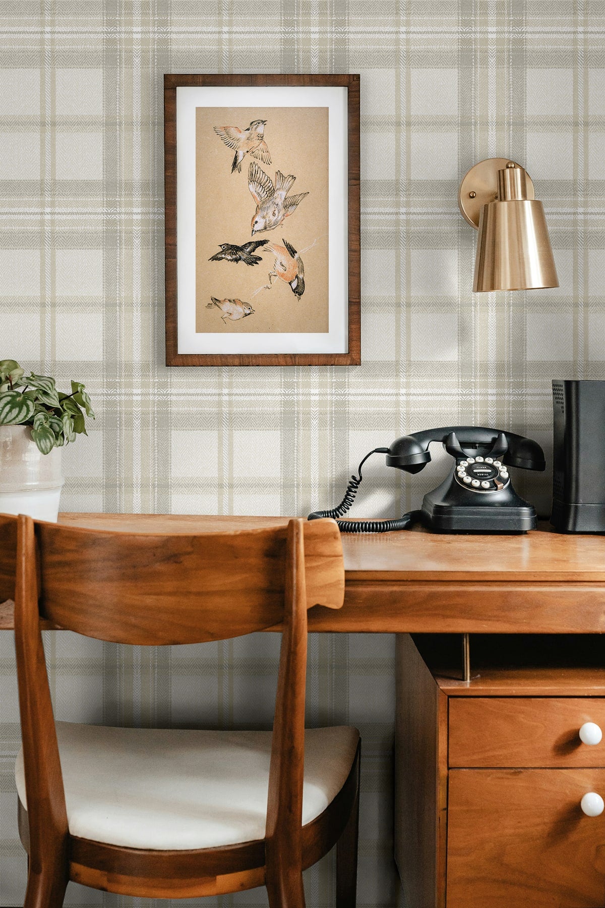 Wooden desk with chair, framed artwork, and vintage telephone against a wall decorated with Gray Broken Twill Plaid Peel & Stick Casa Mia Wallcovering.