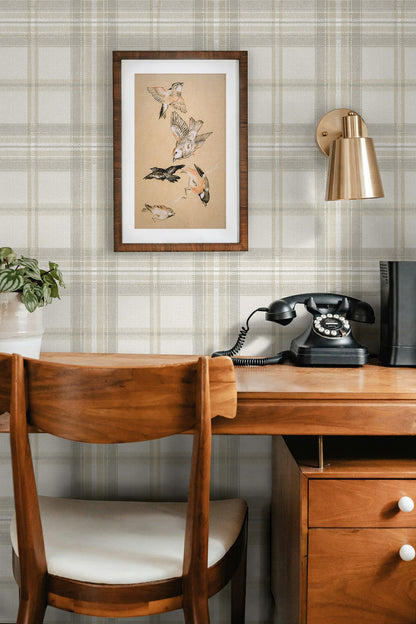 Wooden desk with chair, framed artwork, and vintage telephone against a wall decorated with Gray Broken Twill Plaid Peel & Stick Casa Mia Wallcovering.