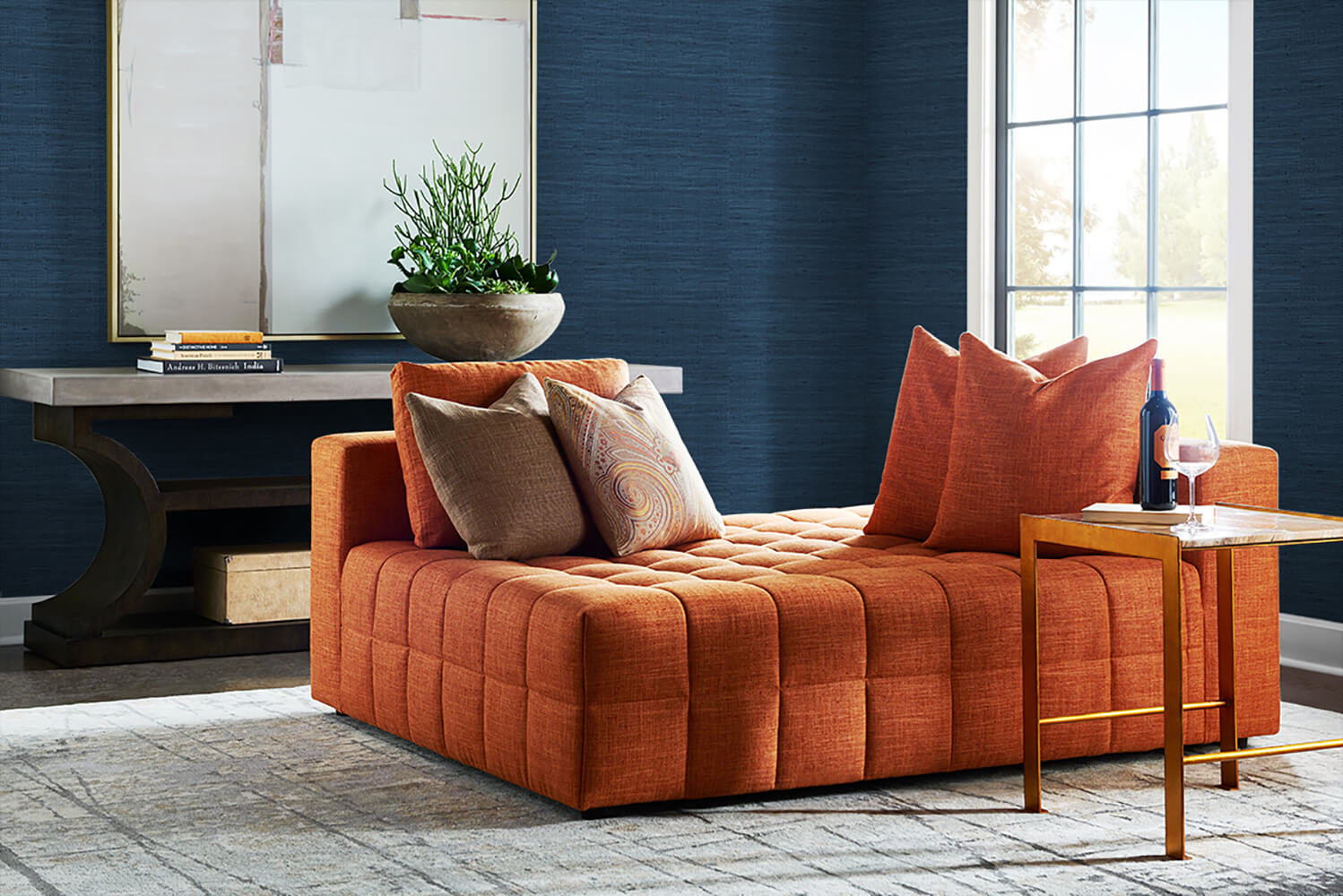 Orange sofa with decorative pillows in a living room setting with wall decorated Blue Weave Grasscloth Effect Peel & Stick Casa Mia Wallcovering.
