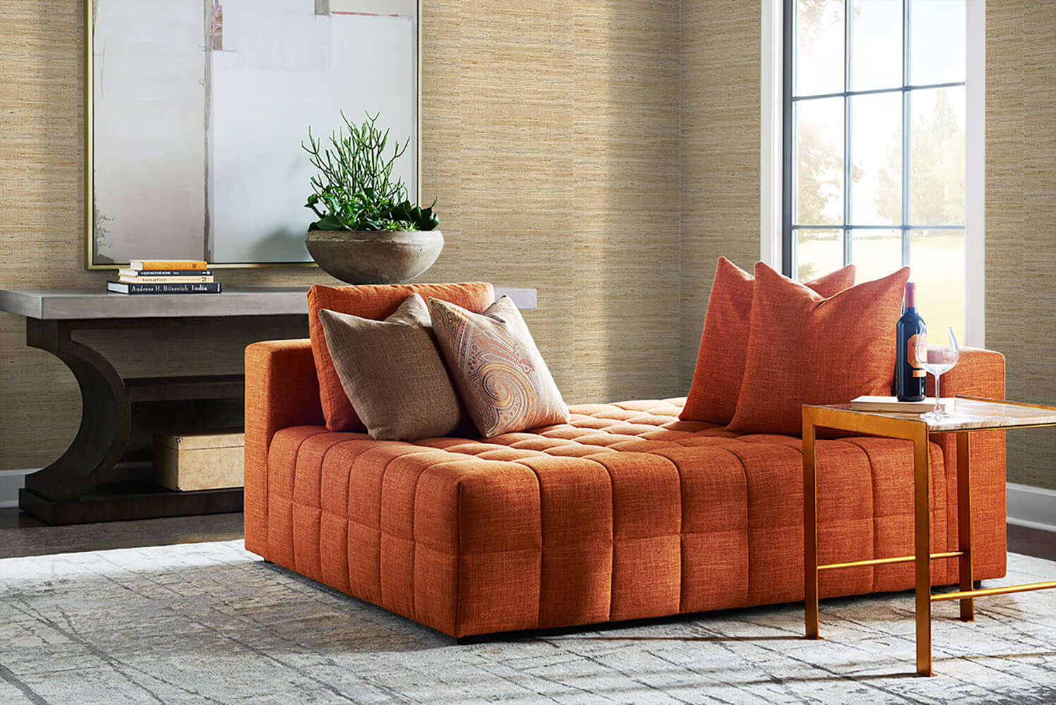 Orange sofa with decorative pillows in a living room setting with wall decorated Beige Weave Grasscloth Effect Peel & Stick Casa Mia Wallcovering.