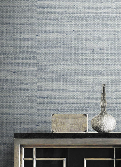 Textured wall decorated with Light Blue Weave Grasscloth Effect Peel & Stick Casa Mia Wallcovering and with decorative items on a dark surface.