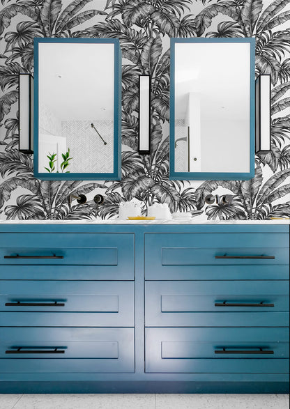 Blue vanity with mirrors against a wall decorated with Black Rainforest Palm Peel & Stick Casa Mia Wallcovering.